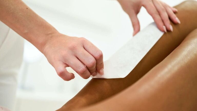 Épilation des jambes d'une femme de carnation matte par une esthéticienne